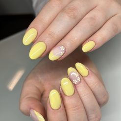 Geelilakkaus vahvistuksella asiakkaan omiin luonnonkynsiin keltaisella sävyllä ja kukkakoristeilla Lxry Beauty Lappeenranta